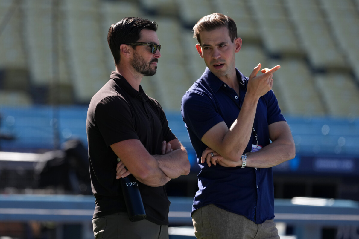 Jun 16, 2026; Los Angeles, California, USA; Los Angeles Dodgers general manager Brandon Gomes (left) talks with Spectrum SportsNet LA play-by-play announcer Joe Davis before the game against the Tampa Bay Rays at Dodger Stadium. Mandatory Credit: Kirby Lee-Imagn Images
