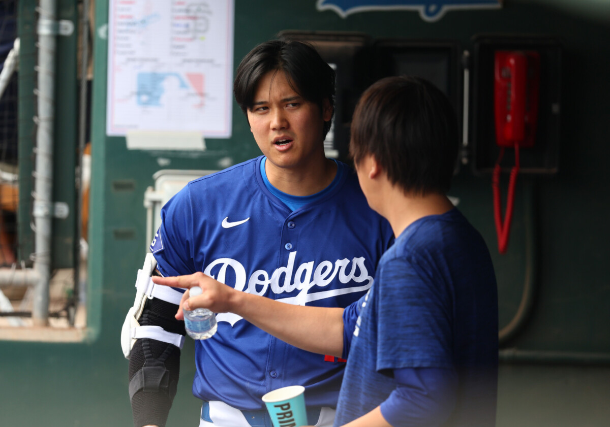 Mar 12, 2024; Phoenix, Arizona, USA; Los Angeles Dodgers designated hitter Shohei Ohtani talks with translator Ippei Mizuhara in the dugout against the San Francisco Giants during a spring training baseball game at Camelback Ranch-Glendale. Mandatory Credit: Mark J. Rebilas-USA TODAY Sports
