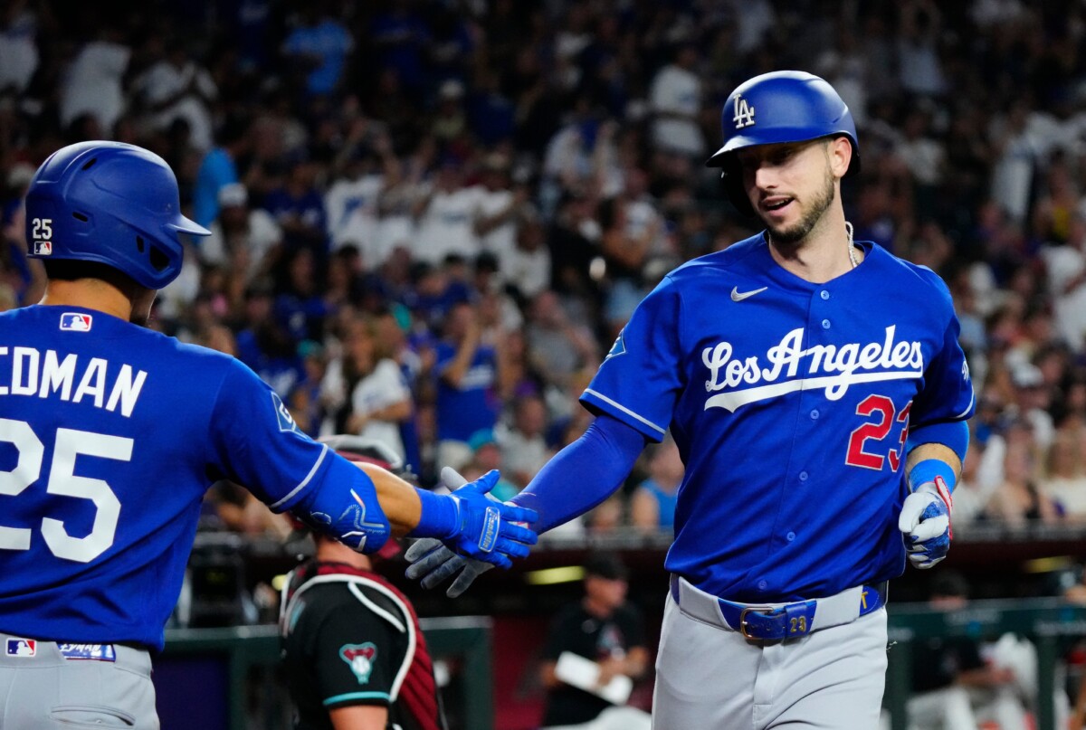 Dodgers outfielder Kyle Tucker (23) high-fives teammate Tommy Edman (25) after a solo home run against Diamondbacks pitcher Jonathan Loaisiga (43) in the eighth inning during a game at Chase Field in Phoenix, Ariz. on August 8, 2026.