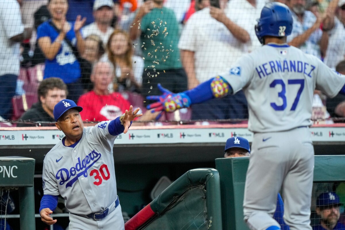 Los Angeles Dodgers manager Dave Roberts (30) throws a handful of sunflower seeds at left fielder Teoscar Hernández (37) after a solo home run in the fourth inning of the MLB National League game between the Cincinnati Reds and the Los Angeles Dodgers at Great American Ball Park in Cincinnati on Monday, Sept. 14, 2026.