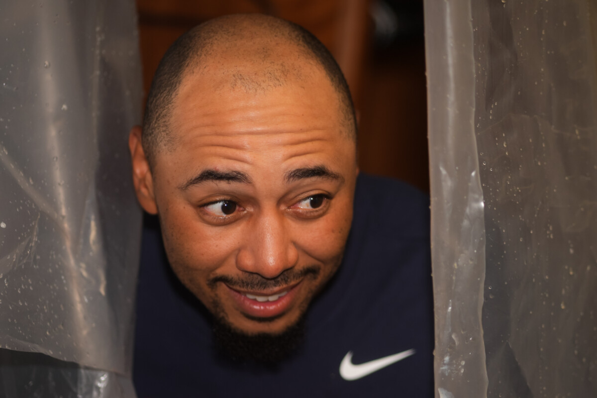 Sep 17, 2026; Cincinnati, Ohio, USA; Los Angeles Dodgers shortstop Mookie Betts hides behind a plastic tarp as his team celebrates after clinching the National League West title at Great American Ball Park. Mandatory Credit: Aaron Doster-Imagn Images